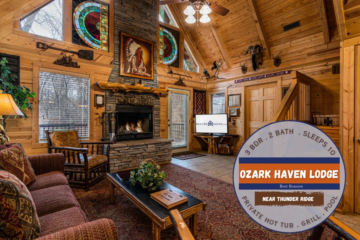 A cozy loft area with a fireplace as the focal point, accented by stained glass windows and exposed wooden beams. Comfortable seating, including a sofa, is arranged for group gatherings or quiet relaxation. The windows offer glimpses of the natural woodland outside, and the warm, inviting decor suggests a space designed for family time and playful activities.