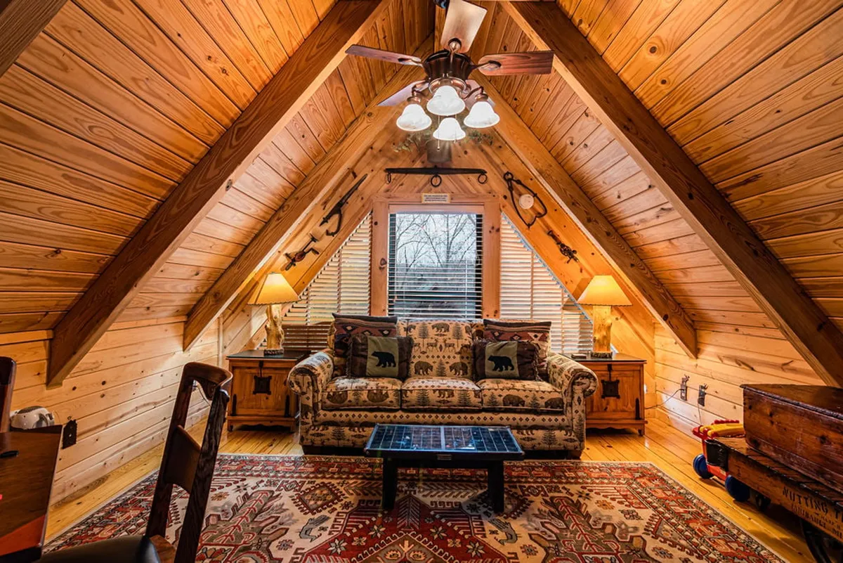 A comfortable living space with a wildlife-themed fabric sofa, exposed wooden ceiling beams, an ornate coffee table, and soft lamp lighting. The room invites relaxation, conversation, and group activities after a day of adventure.