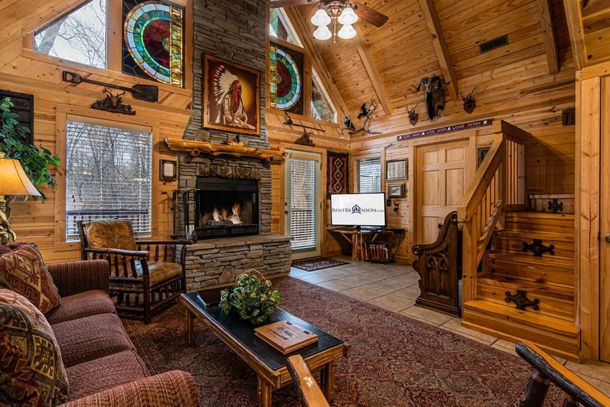 The hero image showcases the warm and inviting interior of the Ozark Haven cabin, featuring a glowing stone fireplace, vibrant stained glass windows, a beautifully crafted wooden staircase, and a cozy seating area with a plush sofa and rustic coffee table. The scene exudes comfort and elegance, blending upscale rustic decor with touches of artistry and craftsmanship.